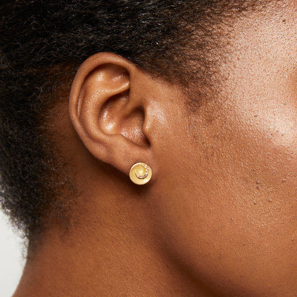 A pair of yellow gold brushed swirl stud earrings with cubic zirconia accents.