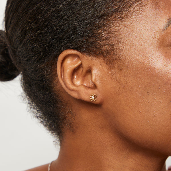 A pair of yellow gold flower-shaped stud earrings with a central cubic zirconia-JOOLS by Jenny Brown