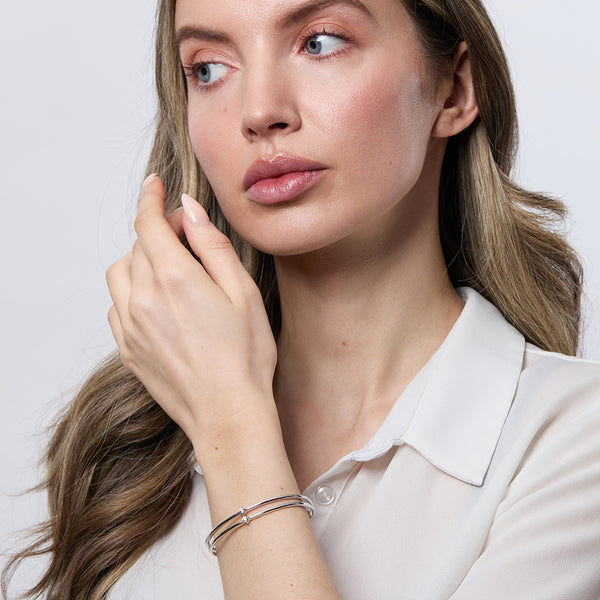 Model wearing A sterling silver bangle bracelet with a two-row solid pattern set with cubic zirconia stones-JOOLS by Jenny Brown