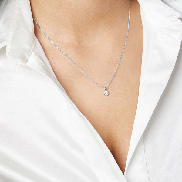 A sterling silver solitaire pendant with a round quarter carat cubic zirconia stone, attached to a silver chain.