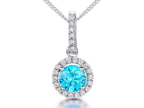 A sterling silver halo pendant with a round brilliant cuut turquoise blue center stone, surrounded by smaller clear cubic zirconia stones, attached to a silver chain.