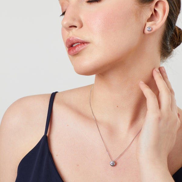  model wearing a pair of 1 carat solitaire cubic zirconia stud earrings in a bezel setting on sterling silver.