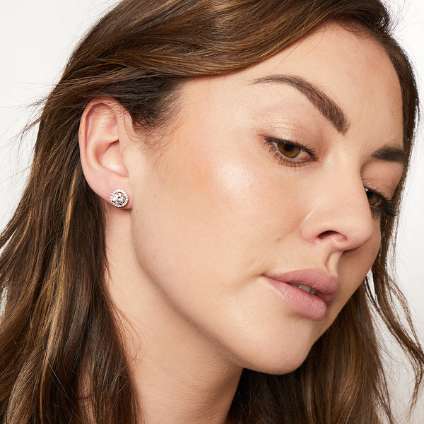 A pair of sterling silver halo style stud earrings with a central cubic zirconia stone surrounded by smaller cubic zirconia stones, rhodium finished-JOOLS by Jenny Brown