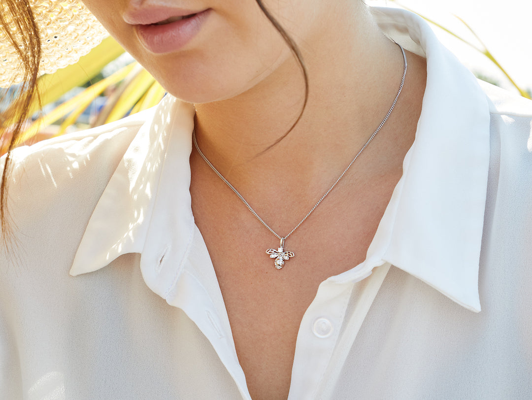 A sterling silver necklace with a bee-shaped pendant encrusted with cubic zirconia, on a chain.