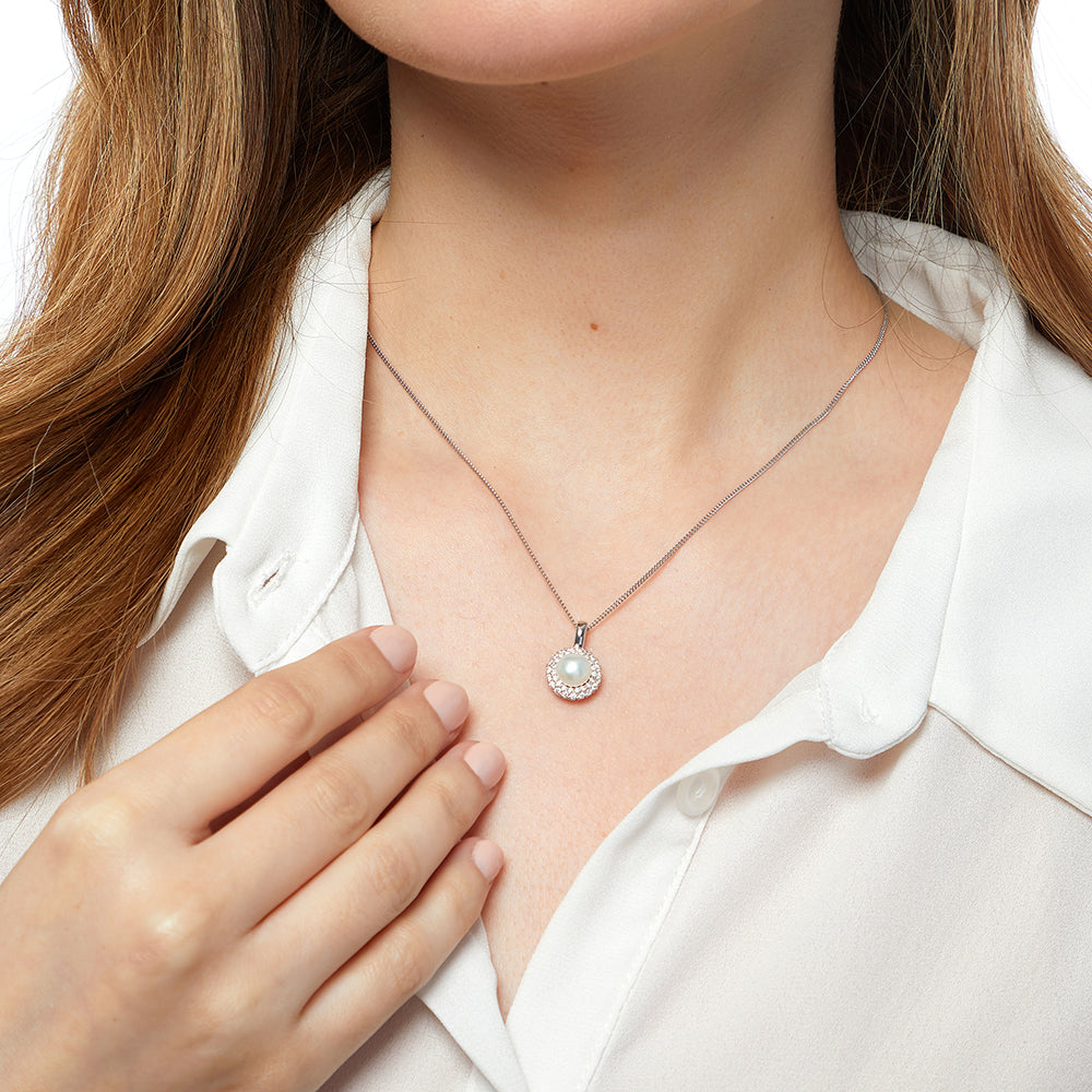 A sterling silver pendant with a central white freshwater pearl surrounded by a halo of cubic zirconia stones, on a silver chain-JOOLS by Jenny Brown