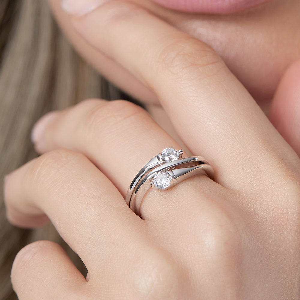 Polished 925 sterling silver bypass ring featuring a double band crossover wave design set with two round brilliant cut cubic zirconia stones.
