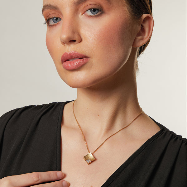 A yellow gold diamond offset textured square pendant on a 16-inch box chain.