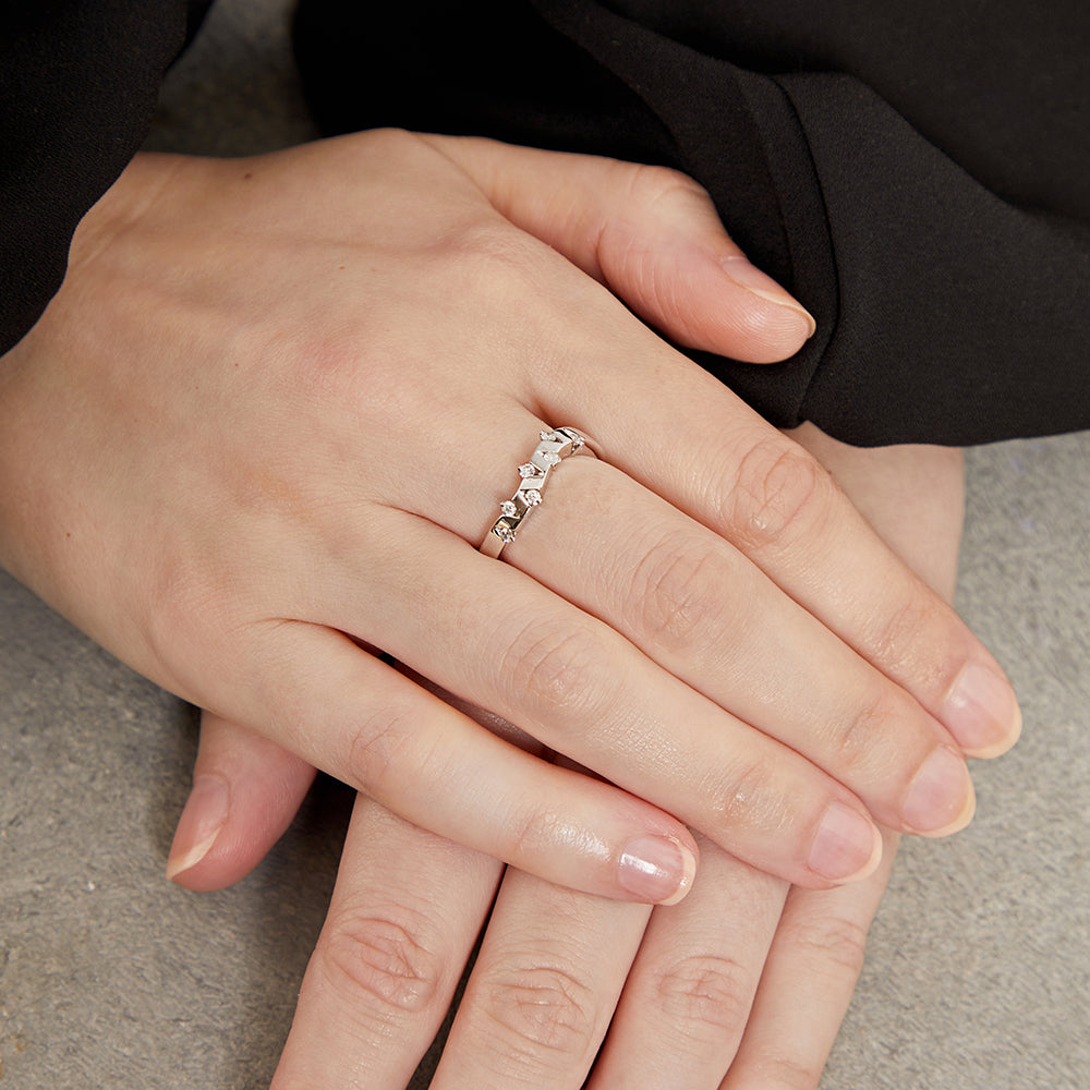 An 18 carat white gold ring with a zig zag diamond pattern and a wave band design, containing seven round cut diamonds.
