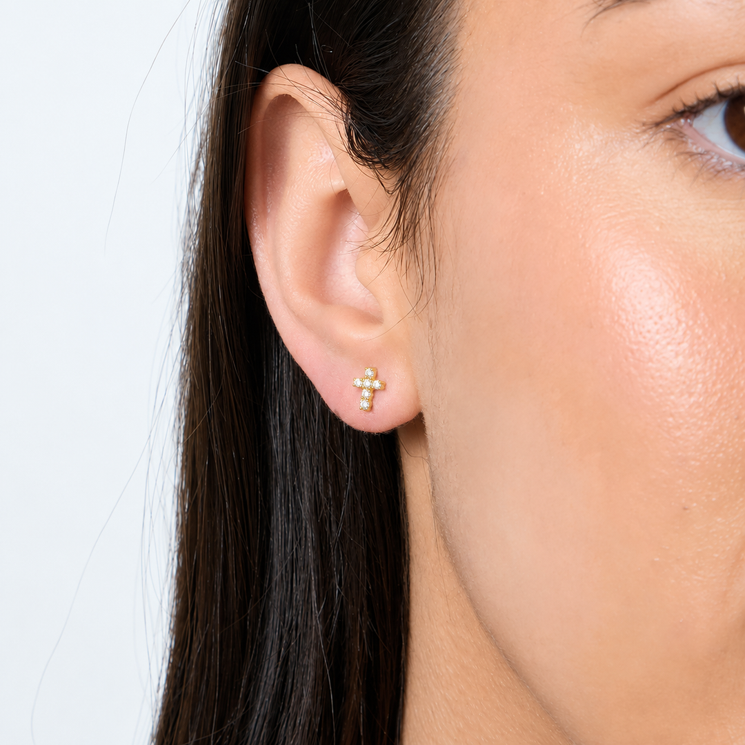 close up of model  wearing Dainty 18ct yellow gold vermeil cross studs set with small round cubic zirconia.