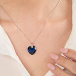 Load image into Gallery viewer, A sterling silver necklace with a large faceted heart-shaped sapphire blue cubic zirconia pendant, accompanied by smaller clear cubic zirconia accents at the top.
