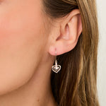 Load image into Gallery viewer, A pair of sterling silver heart-shaped drop earrings with a cubic zirconia in the center, dangle style.- JOOLS by Jenny Brown
