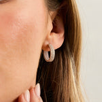 Load image into Gallery viewer, A pair of sterling silver huggie hoop earrings encrusted with cubic zirconia stones-JOOLS by Jenny Brown
