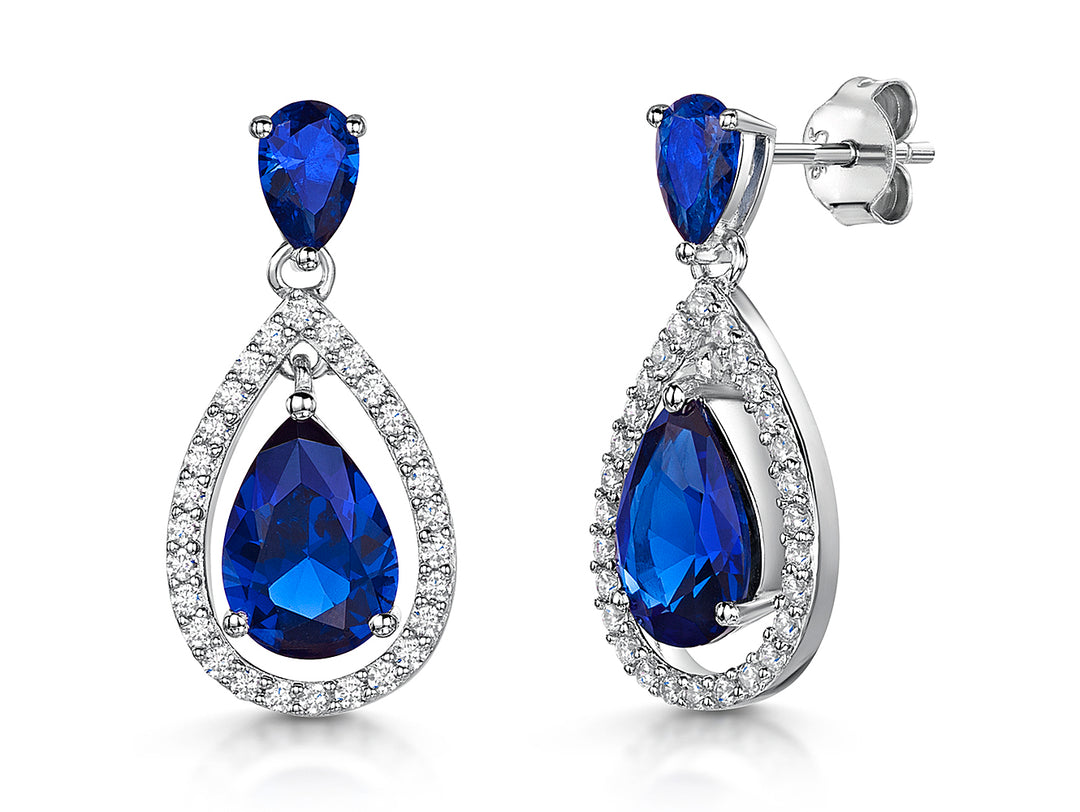 A pair of sterling silver teardrop earrings featuring deep blue sapphire cubic zirconia with a halo of smaller cubic zirconia stones around the edge.