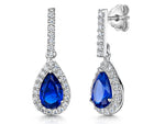 Load image into Gallery viewer, A pair of sterling silver drop earrings with sapphire blue cubic zirconia and smaller clear cubic zirconia accents along the teardrop shape.

