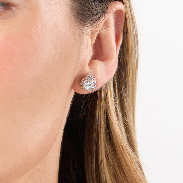 A pair of sterling silver swirl solitaire stud earrings with a clear central cubic zirconia stone surrounded by smaller clear stones - JOOLS By Jenny Brown