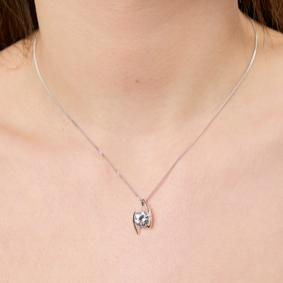 A sterling silver 2 carat  solitaire pendant with a round cubic zirconia stone offset held by two silver bars, on a chain-JOOLS by Jenny Brown