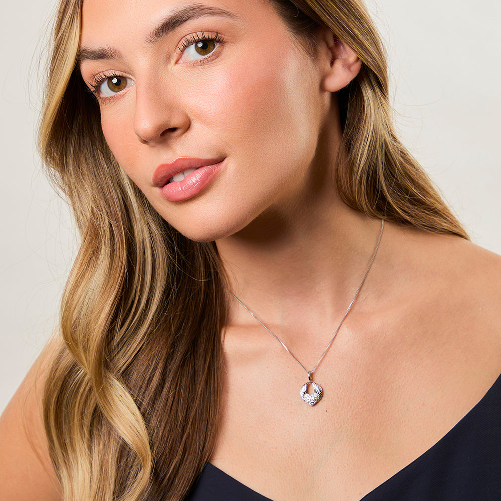 A sterling silver pendant featuring angel wings surrounding a heart-shaped pave with cubic zirconia  stones- JOOLS by Jenny Brown