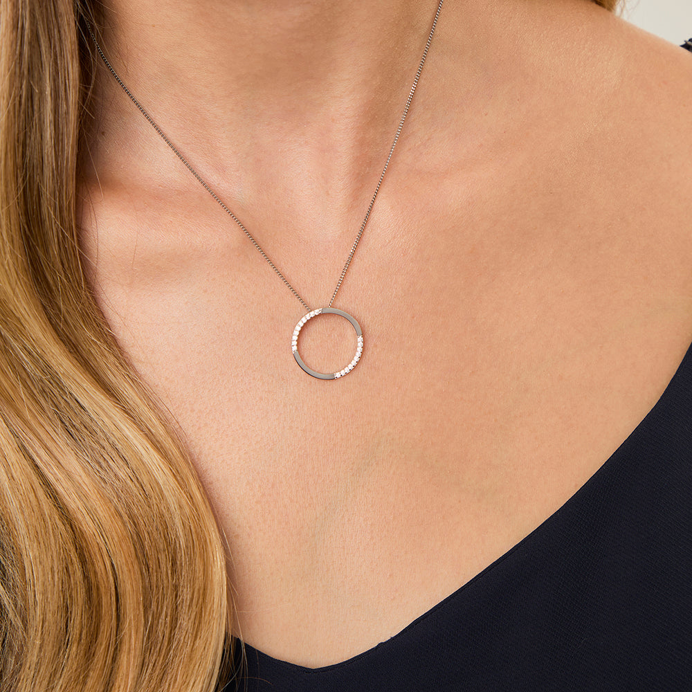 A sterling silver open circle pendant with cubic zirconia stones set in a semi-polished finish, attached to a silver chain.-JOOLS by Jenny Brown