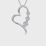 Load and play video in Gallery viewer, A sterling silver heart-shaped pendant with three cubic zirconia stones set within it, attached to a silver chain-  JOOLS By Jenny Brown

