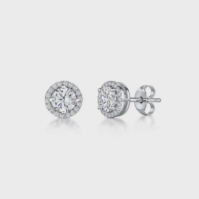 A pair of sterling silver halo style stud earrings with a central cubic zirconia stone surrounded by smaller cubic zirconia stones, rhodium finished-JOOLS by Jenny Brown