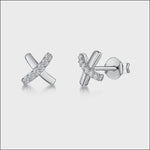 Load and play video in Gallery viewer, A pair of sterling silver stud earrings in a kiss or X-shape design, encrusted with cubic zirconia stones.- JOOLS By Jenny Brown

