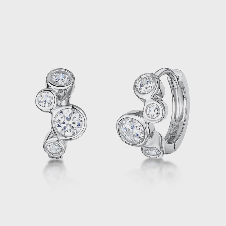Pair of sterling silver huggie earrings featuring round clear cubic zirconia stones 