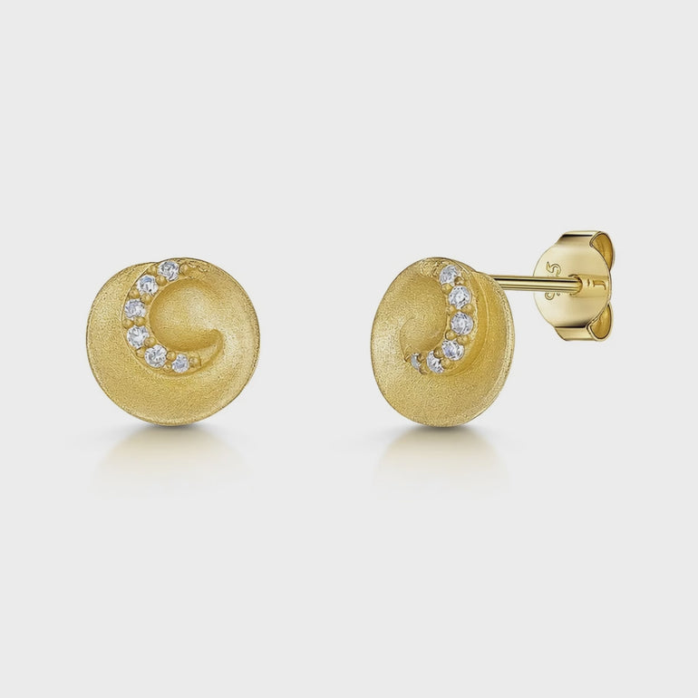 A pair of yellow gold brushed swirl stud earrings with cubic zirconia accents.