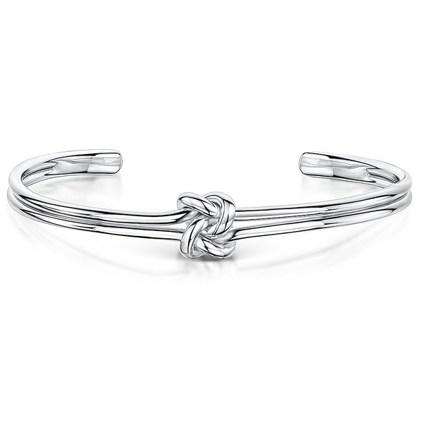 A polished silver-tone open cuff bracelet featuring a central love-knot motif. The band appears as two parallel rounded wires that loop into the knot at the center, tapering to smooth, rounded ends for an easy slip-on fit-JOOLS by Jenny Brown